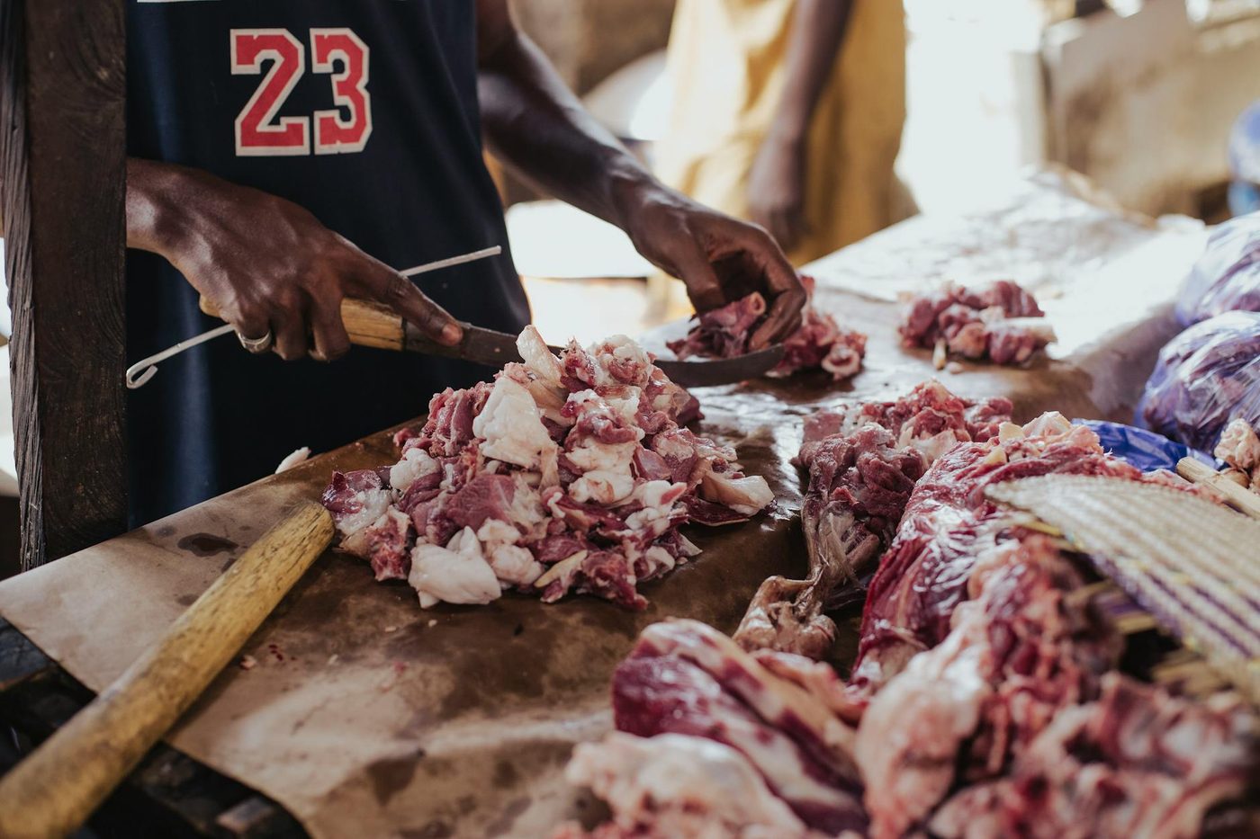 Boucher de la Maison Bréval découpant une pièce de viande à l'étal, à Dakar